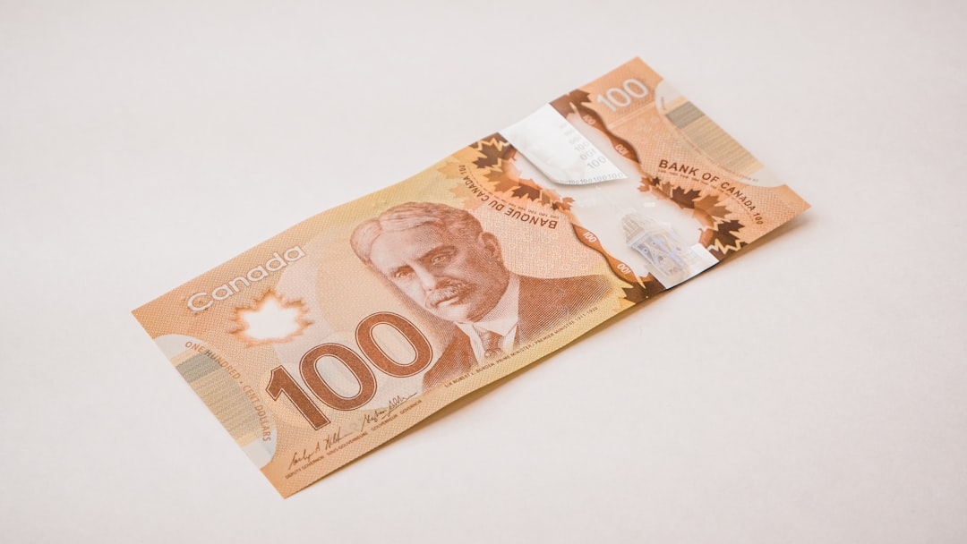 a Canadian 100 dollar bill with a knife sticking out of it