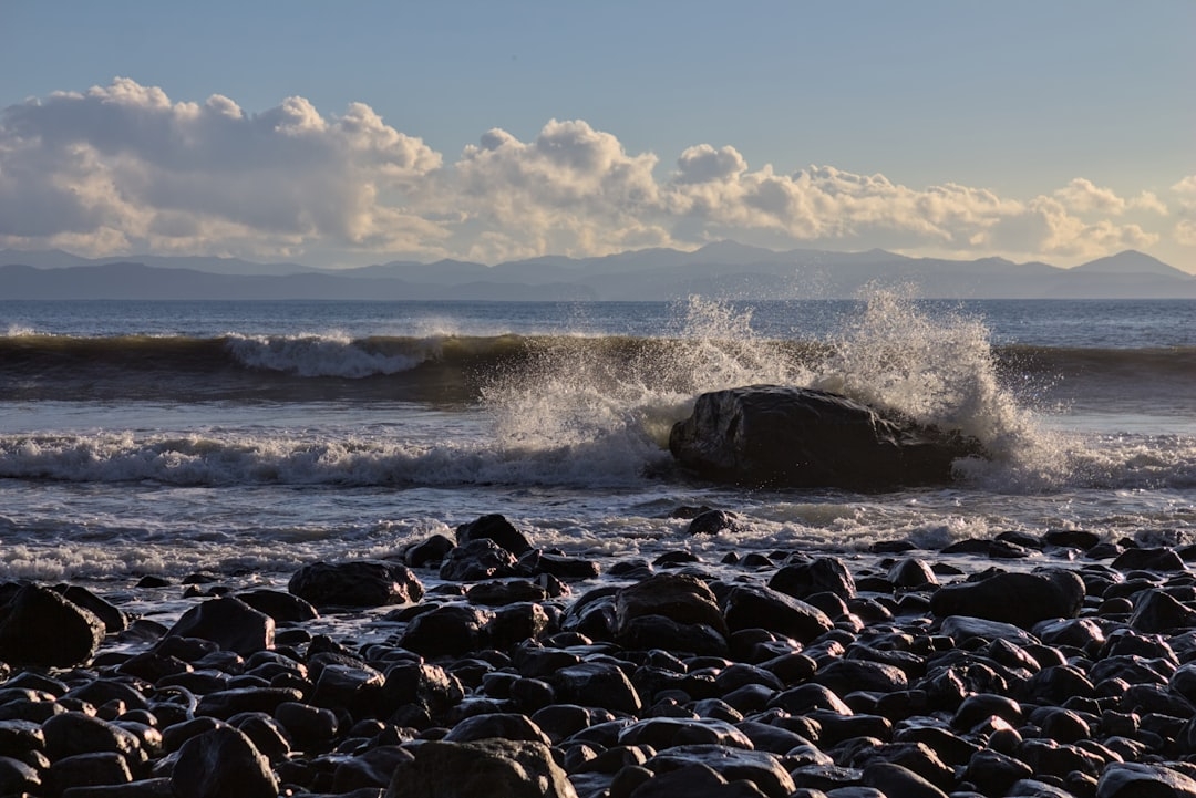 a large rock sitting on top of a beach next to the ocean