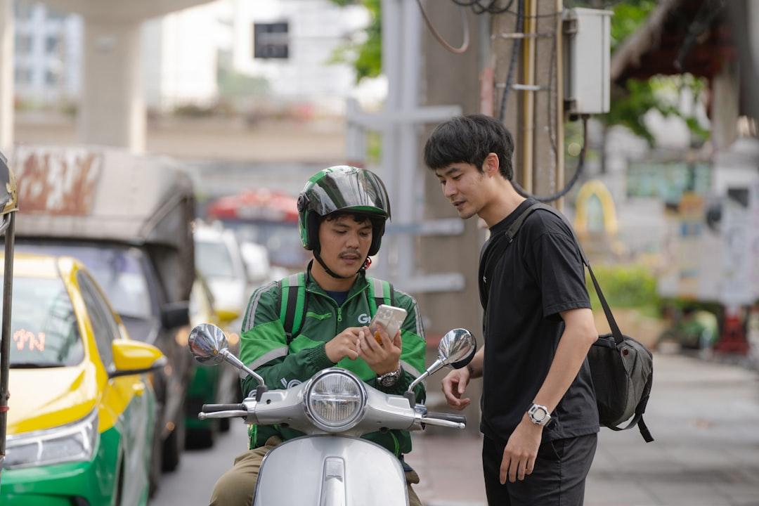 a man standing next to a man on a scooter