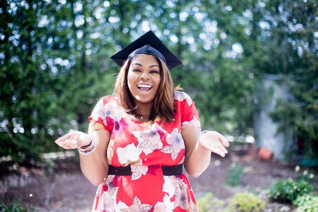 woman wearing academic hat standing in garden showing palm at daytime