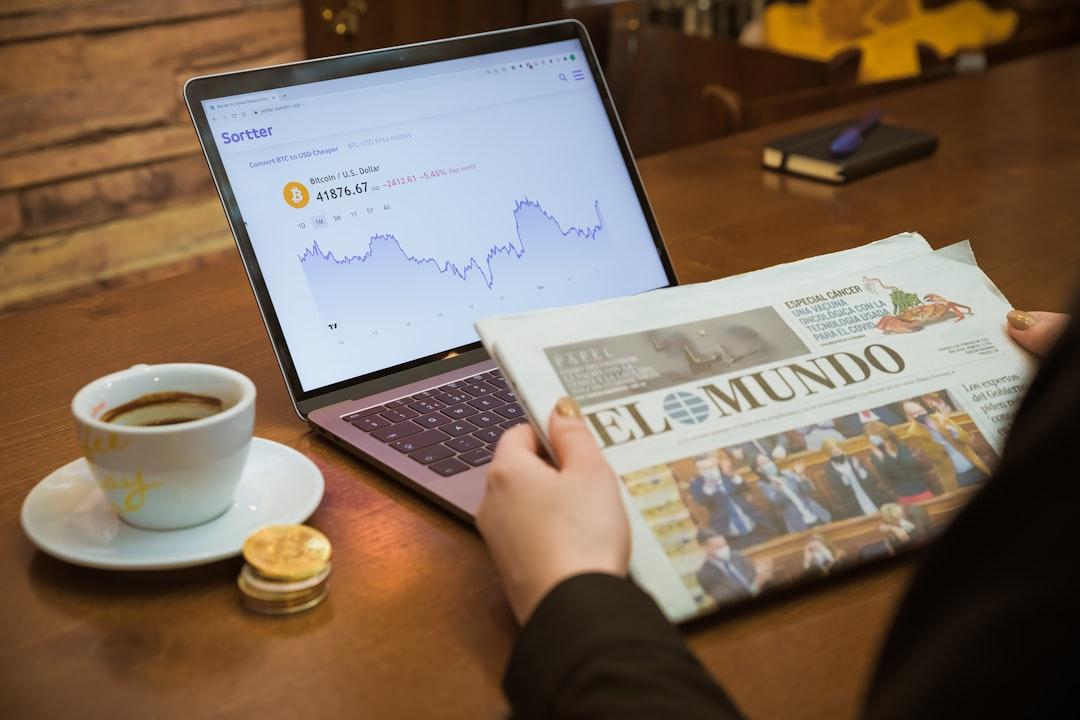 a person reading a newspaper next to a laptop